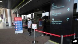 A masked man walks out of an area of thermo scan at the quiet Phnom Penh International Airport in Phnom Penh, Cambodia, Friday, April 3, 2020. Cambodia issued travel restrictions in order to reduce and contain the transmission of the new coronavirus. (AP Photo/Heng Sinith)