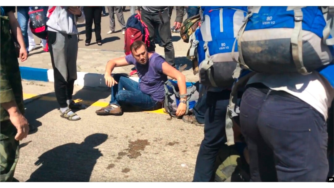 FILE - In this frame from video provided by Anapa Today, opposition leader Alexei Navally, center, tries to get up after being attacked at the Anapa airport, southern Russia, May 17, 2016.