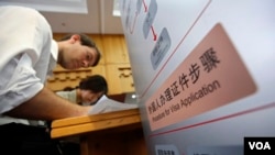 外籍人士在北京市公安局入出境管理處服務中心填寫表格。