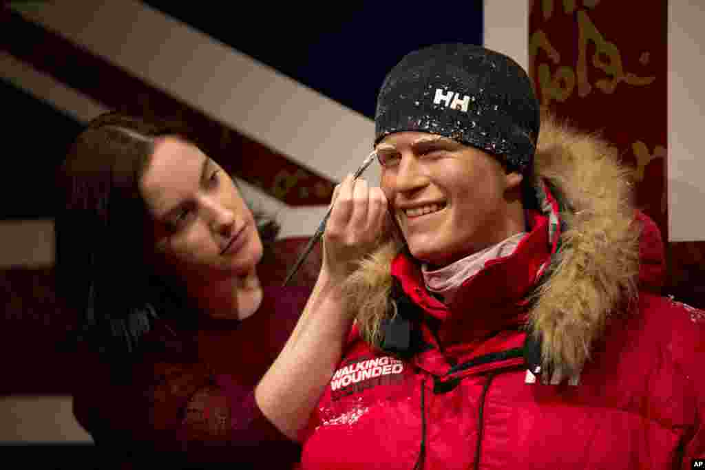 A Madame Tussauds artist poses for photographers with a waxwork of Britain&#39;s Prince Harry dressed for a trek to the South Pole during a photocall at the attraction&#39;s premises in London.