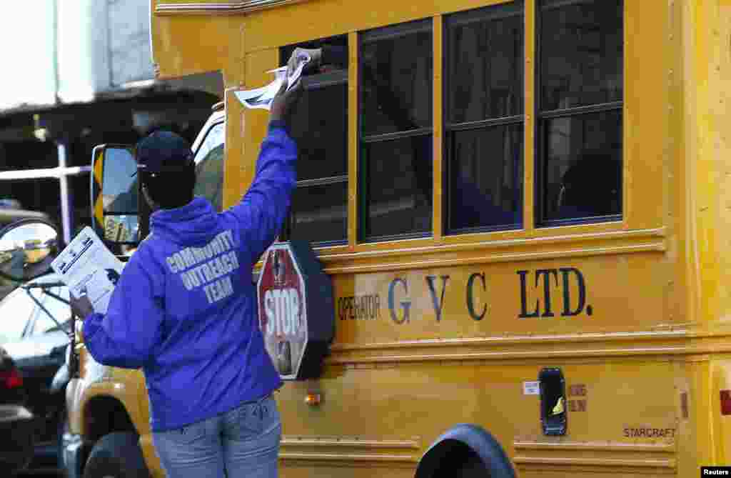 A New York City Health department official hands out information on the Ebola virus to people riding on a school bus in the Bronx, New York, Oct. 27, 2014.