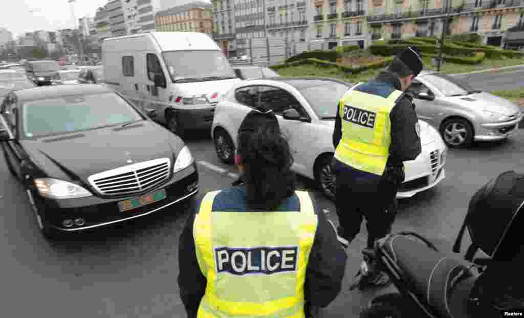 Polisi mengecek mobil untuk memeriksa pelat nomor di Porte Maillot, Paris (17/3). Pemerintah Perancis menurunkan ratusan polisi di Paris untuk memberlakukan aturan paling ketat dalam pembatasan mobil di jalan. (Reuters/Philippe Wojazer)
