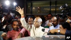 FILE - Ram Nath Kovind, center, waves to media upon arrival at the airport in New Delhi, India, June 19, 2017.