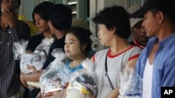 Migrant workers from Burma, who were trapped in floods and have been out of work for weeks, hold food rations in Thailand's Ayutthaya province November 1, 2011. 