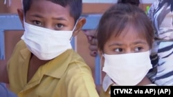 In this November 2019, image from video, masked children wait to get vaccinated against measles at a health clinic in Apia, Samoa.