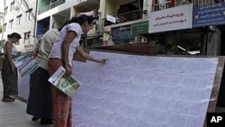 Women search their names in the list of eligible voters outside a local election commission office in downtown Rangoon, Burma, 21 Sept 2010