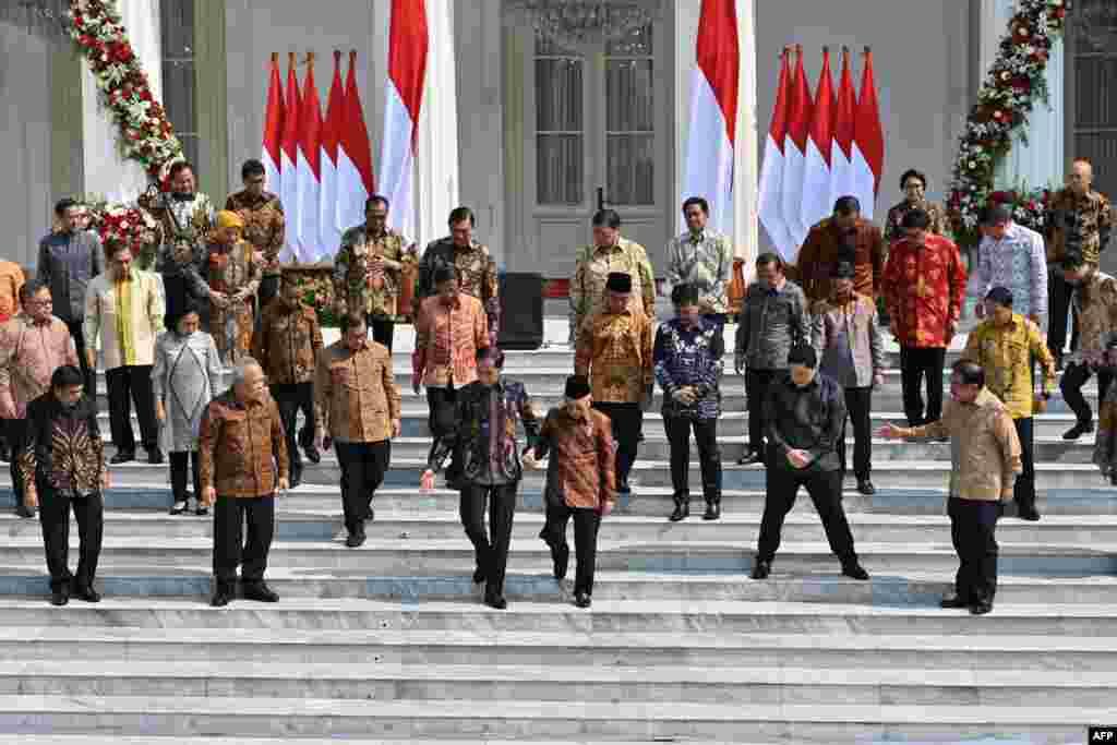 Presiden Joko Widodo (tengah kiri) menggandeng Wakil Presiden Ma&#39;ruf Amin (tengah kanan)&nbsp; sebelum sesi foto dengan anggota kabinet baru di tangga Istana Merdeka, 23 Oktober 2019. (Foto: AFP)