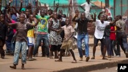 Angry supporters of opposition leader Kizza Besigye confront military police firing warning shots, near to his party headquarters, in Kampala, Uganda, Feb. 19, 2016. 