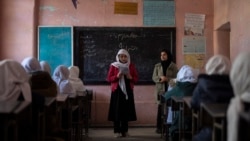 An Afghan girl reads in a classroom next to her teacher at Tajrobawai Girls High School, in Herat, Afghanistan, Nov. 25, 2021.