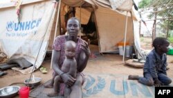 FILE - A woman and her children displaced by fighting in South Sudan sit outside her tent at the Kule camp for Internally Displaced People at the Pagak border crossing in Gambella, Ethiopia, July 10, 2014.