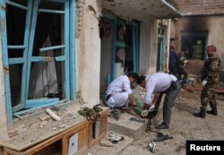 FILE - Afghan officials inspect the site of a suicide bomb attack outside a Shi'ite mosque in Herat, Afghanistan, March 25, 2018.