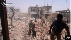 Citizen journalism image provided by Qusair Lens, which has been authenticated based on its contents and other AP reporting, shows Syrians inspecting the rubble of damaged buildings due to government airstrikes, in Qusair, Homs province, Syria, May 18, 201