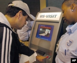 FILE - Department of Homeland Security official (r) assist a passenger (l) as he scans his fingerprint on a machine, part of the exit process at Hartsfield-Jackson Atlanta International Airport in Atlanta.