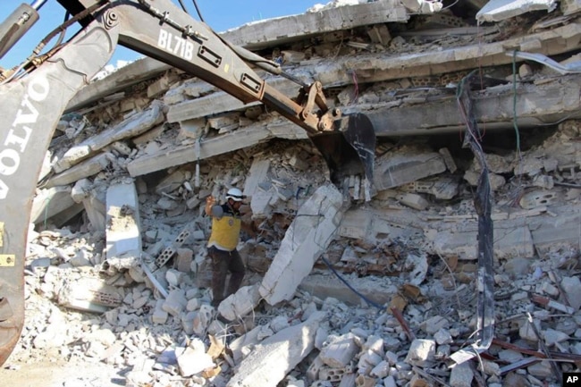 ພາບທີ່ໄດ້ຮັບຈາກກຸ່ມປ້ອງກັນພົນລະເຮືອນໝວກຂາວ (Syrian Civil Defense White Helmets), ທີ່ຖືວ່າເປັນ ກຸ່ມແທ້ຈິງ ແລະພວກລາຍງານຂອງອົງການຂ່າວເອພີ, ສະແດງ ໃຫ້ເຫັນພວກພະນັກງານຂອງກຸ່ມດັ່ງກ່າວ ເຮັດວຽກໃນສະຖານທີ່ເກີດເຫດ, ຊີເຣຍ, 12 ສິງຫາ 2018.
