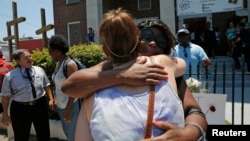 지난해 6월 미국 노스캐로라이나 찰스톤에서 총기난사 사건이 발생한 가운데 사건이 발생한 교회 밖에서 유가족들이 포옹하고 있다.