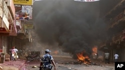Uganda Police patrol as tires burn in the capital city Kampala, April 29, 2011 after riots broke out
