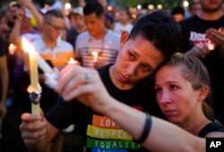 FILE - People hold candles during a vigil downtown for the victims of a mass shooting at the Pulse nightclub in Orlando, Florida, June 13, 2016.