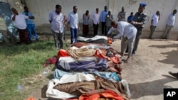 Somalis observe bodies that were brought to and displayed at a Mogadishu hospital, Aug. 25, 2017. 