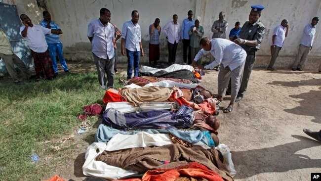 Somalis observe bodies that were brought to and displayed at a Mogadishu hospital, Aug. 25, 2017. 