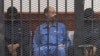 FILE - Saif al-Islam Gadhafi in the accused cell as he stands trial for illegally trying communicating with the outside world in June of 2012, Zintan, Libya, May 2, 2013.