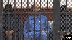 FILE - Saif al-Islam Gadhafi in the accused cell as he stands trial for illegally trying communicating with the outside world in June of 2012, Zintan, Libya, May 2, 2013.
