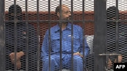 Saif al-Islam Gadhafi in the accused cell as he stands trial for illegally trying communicating with the outside world in June of 2012, Zintan, Libya, May 2, 2013.