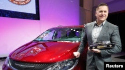 Tim Kuniskis, Head of Passenger Car Brands - Dodge, SRT, Chrysler and Fiat, FCA - N. America, poses with the award for the Chrysler Pacifica as 2017 Utility Vehicle of the Year during the N. American International Auto Show in Detroit, Jan. 9, 2017.