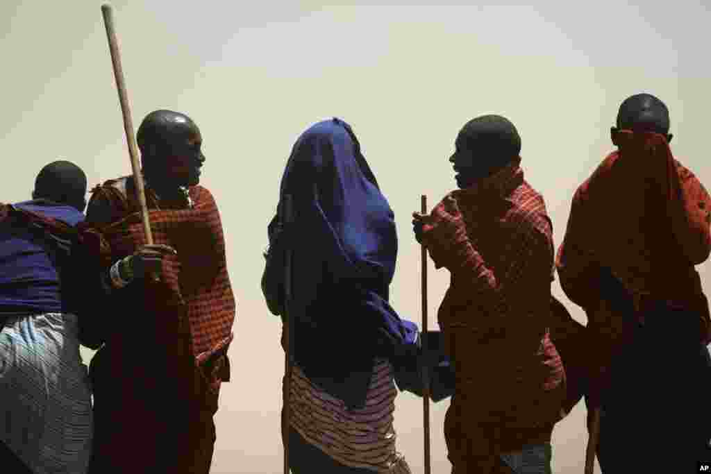 Des membres de la tribu Maasai se couvrent le visage se protégeant contre une tempête de sable dans un village à la périphérie de Serengeti, dans le nord de la Tanzanie. Les Massaïs sont un peuple semi-nomades qui migrent d&#39;un endroit à l&#39;autre.