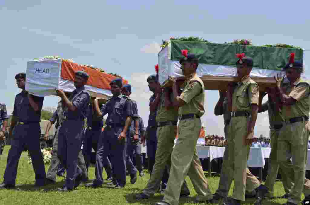 Petugas keamanan India mengusung peti mati yang berisi jasad para korban helikopter yang jatuh dalam misi penyelamatan banjir&nbsp; di Dehradun, India utara. Helikopter angkatan udara itu menghantam sisi gunung dan jatuh ke sungai pada hari Selasa, menewaskan lima anggota kru dan tiga orang warga sipil dalam pesawat itu.