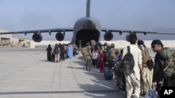 In this image provided by the U.S. Air Force, U.S. Air Force loadmasters and pilots assigned to the 816th Expeditionary Airlift Squadron, load people being evacuated from Afghanistan onto a U.S. Air Force C-17 Globemaster III at Hamid Karzai International