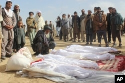 FILE - Afghan villagers gather around victims of clashes between Taliban and Afghan security forces in the Taliban-controlled Buz-e Kandahari village in Kunduz province, Afghanistan, Nov. 4, 2016.