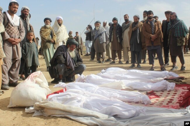 FILE - Afghan villagers gather around victims of clashes between Taliban and Afghan security forces in the Taliban-controlled Buz-e Kandahari village in Kunduz province, Afghanistan, Nov. 4, 2016.