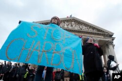 FILE - Environmental activists display a banner as they protest in support of the Paris climate accord, at Pantheon monument in Paris, Dec. 12, 2017.