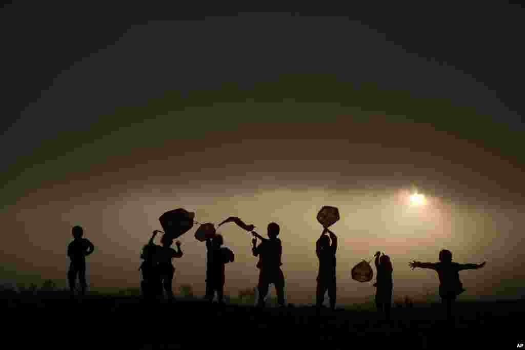 Afghan refugee children play with plastic bags as kites as the sun sets on the outskirts of Islamabad, Pakistan.