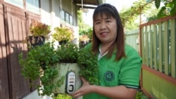 Pa Book resident Saisupan Maneekan shows a broken rice cooker that has been repurposed as a planter.