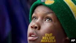 A boy with "Rest In Peace Nelson Mandela" painted on his face looks up to the skies during the memorial service for former South African president Nelson Mandela at the FNB Stadium in Soweto, near Johannesburg, South Africa, Tuesday Dec. 10, 2013. (AP Photo/Peter Dejong)