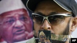 A supporter of veteran Indian social activist Anna Hazare is seen with a photo of Hazare over his mouth during a protest rally against corruption in the northern Indian city of Chandigarh Aug. 17, 2011.