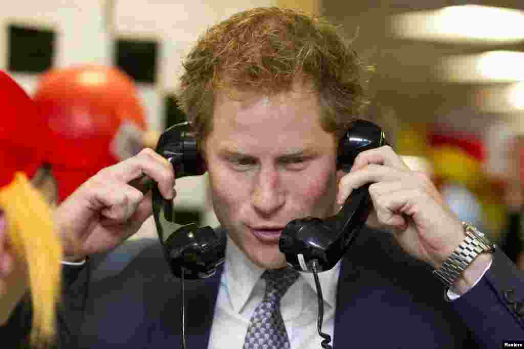 Britain&#39;s Prince Harry speaks on telephones during a charity event in central London.