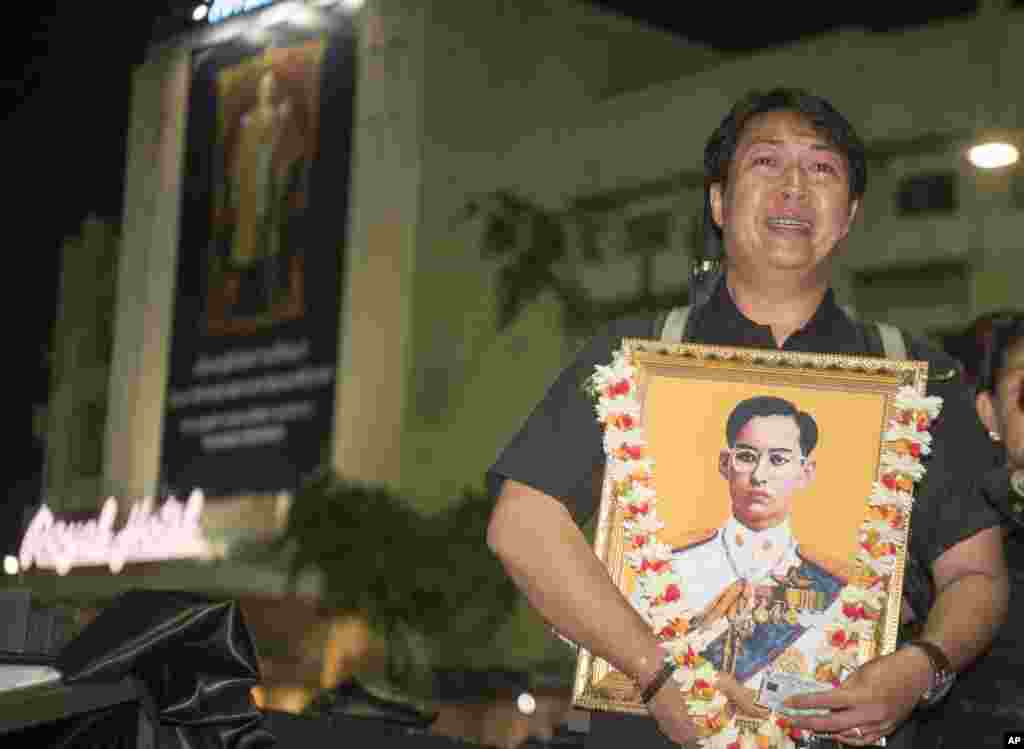 A Thai mourner holds a portrait of the late King Bhumibol Adulyadej in a queue to take part in the Royal Cremation ceremony in Bangkok, Thailand, Wednesday, Oct. 25, 2017. (AP Photo/Kittinun Rodsupan)