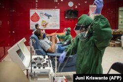 Seorang petugas kesehatan mengoperasikan alat untuk mengumpulkan plasma dari para penyintas COVID-19 di kantor Palang Merah Indonesia di Surabaya, Jawa Timur, 18 September 2020. (Foto: Juni Kriswanto/AFP)