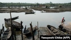 Seorang nelayan berjalan di sungai yang dipenuhi minyak di Desa Ogoniland, dekat Bodo, yang masuk ke dalam wilayah Delta Niger, pada 20 Februari 2019. Aksi kekerasan masih sering terjadi di wilayah Delta Niger. (Foto: AFP/Yasuyoshi Chiba)