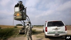 FILE - A National Guardsman checks on his colleague inside a Border Patrol skybox near the Hidalgo International Bridge in Hidalgo, Texas, April 19, 2011. 