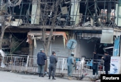 FILE - Afghan policemen inspect the site of bombing attack in Kabul, Afghanistan, Jan. 28, 2018. On Saturday, a car bomb ripped through a crowded area outside a government building, killing more than 100 people. An Afghan offical said that with the attack, the Taliban, which claimed responsibility, crossed a "red line."