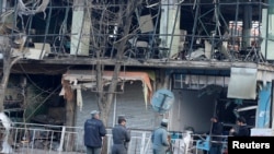 افغان پولیس کے اہلکار 27 جنوری کو ایمبولینس بم حملے میں تباہ ہونے والی ایک عمارت کا معائنہ کر رہے ہیں۔ 