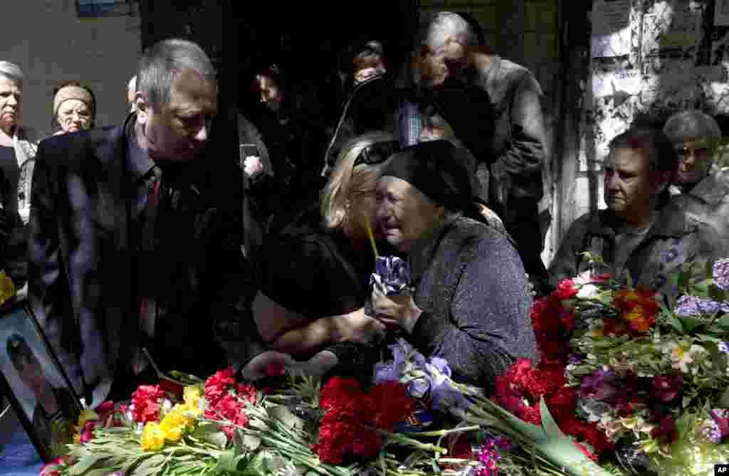 The mother of a Cossack man killed in the burning of the trade union on May 2 holds a candle while crying next to his coffin during the funeral in Odessa, Ukraine, May 8, 2014.
