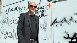Tunisian director Mourad Cheikh walks past a wall covered with graffiti in Tunis, ahead of the screening of his documentary 'No More Fear' - a 74-minute documentary filmed in the midst of the uprising that led to Tunisian President Zine el Abidine Ben Ali