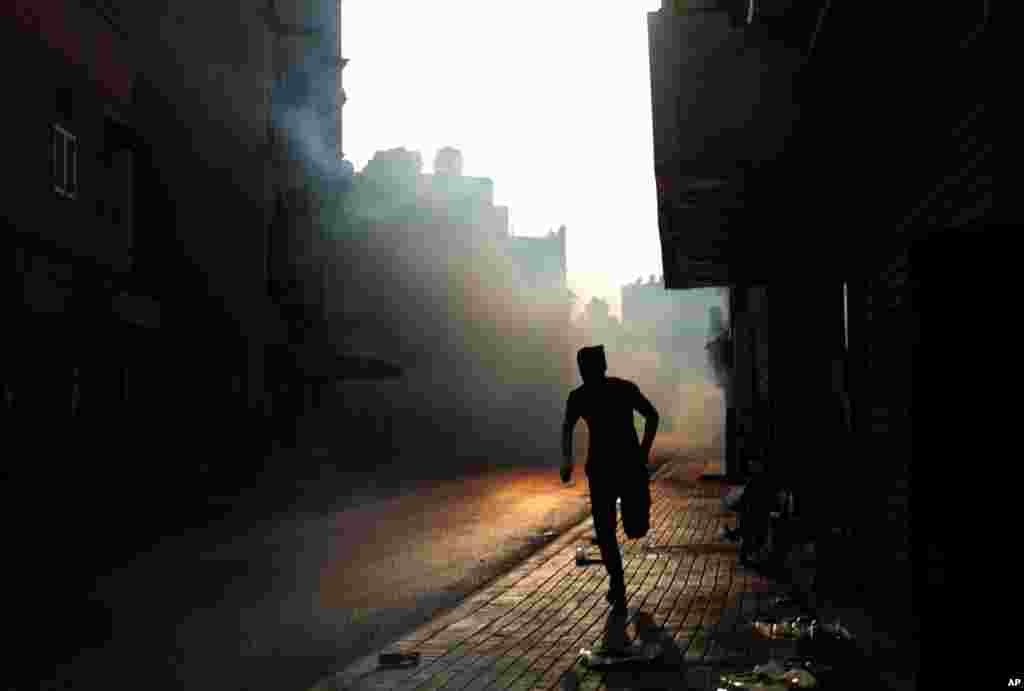 A Bahraini anti-government protester reacts to tear gas fired by riot police during clashes in Bilad al-Qadeem village, Bahrain.