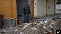 FILE - A member of the Federal Police stands next to unexploded bombs left by Islamic State group militants on the western side of Mosul, Iraq, March 22, 2017.