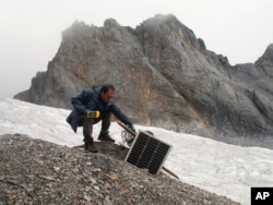 This Sept. 22, 2018 photo shows glaciologist Wang Shijin repairing a broken remote meteorological station on the Baishui Glacier No. 1 on the Jade Dragon Snow Mountain in the southern province of Yunnan in China.