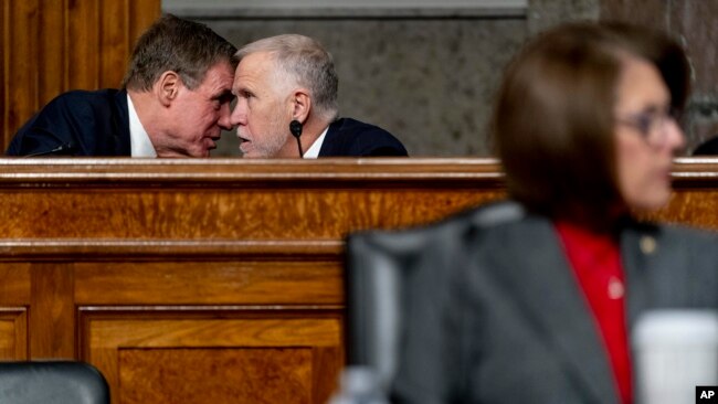 Sen. Mark Warner, D-Va., left, and Sen. Thom Tillis, R-N.C., center, speak together as Treasury Secretary Janet Yellen and Federal Reserve Chairman Jerome Powell testify during a Senate Banking Committee hearing on Capitol Hill, Nov. 30, 2021.